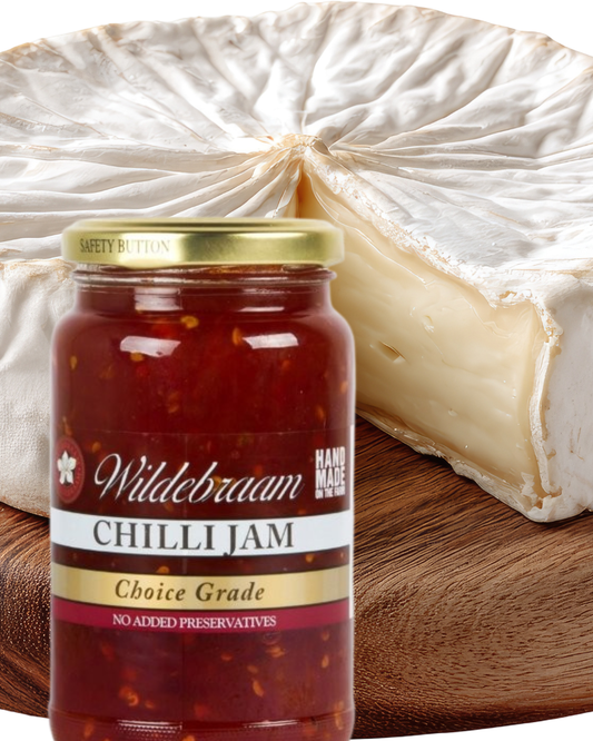 Jar of Wildebraam Chilli Jam with a wheel of cheese in the background