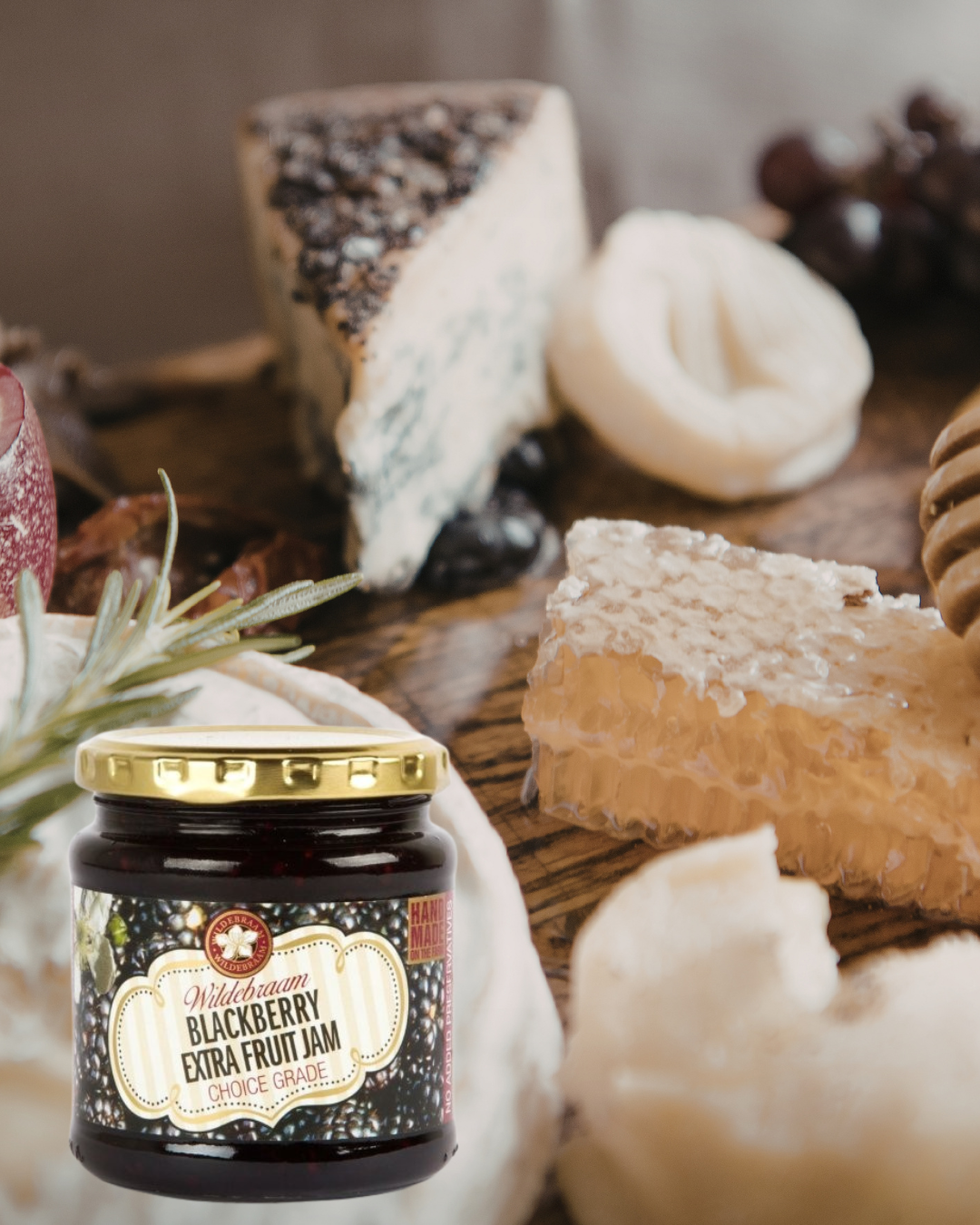 Jar of blackberry extra fruit jam on a table with cheese and honeycomb.