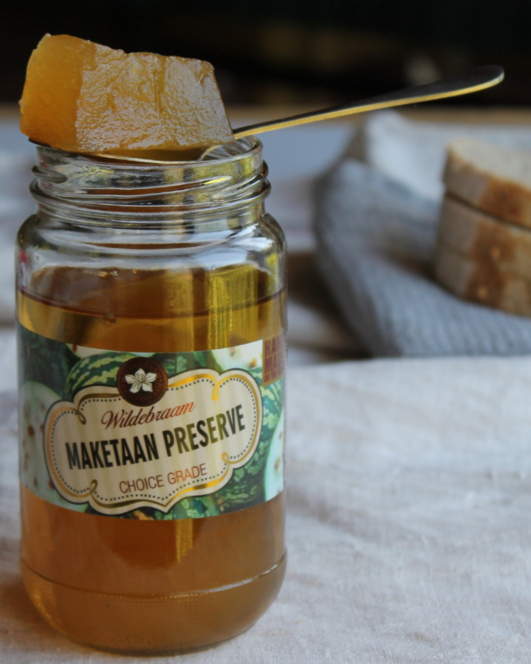 Jar of Maketaan Preserve with a spoonful of preserve on a cloth surface