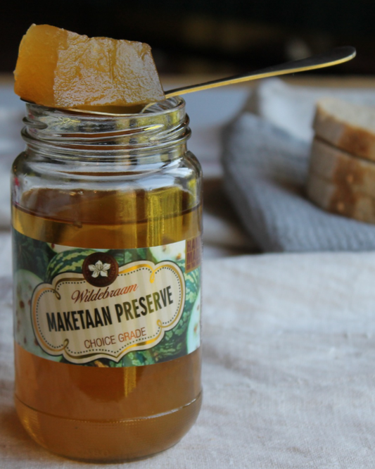 Jar of Maketaan Preserve with a spoonful of preserve on a cloth surface