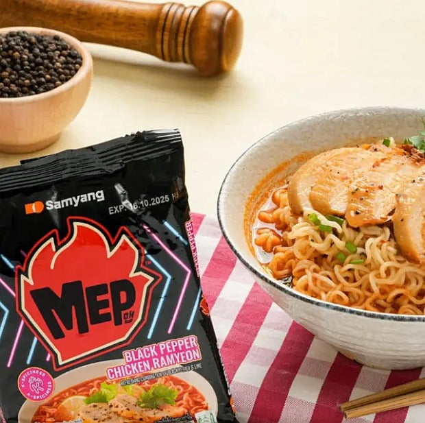 Samyang MEP Black Pepper Chicken Ramyun package with a bowl of noodles on a checkered tablecloth.