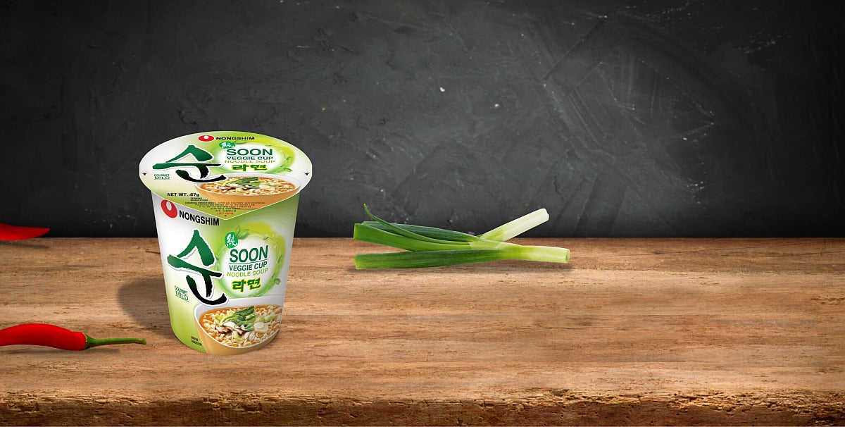 Cup of noodles with green onions on a wooden surface and dark background